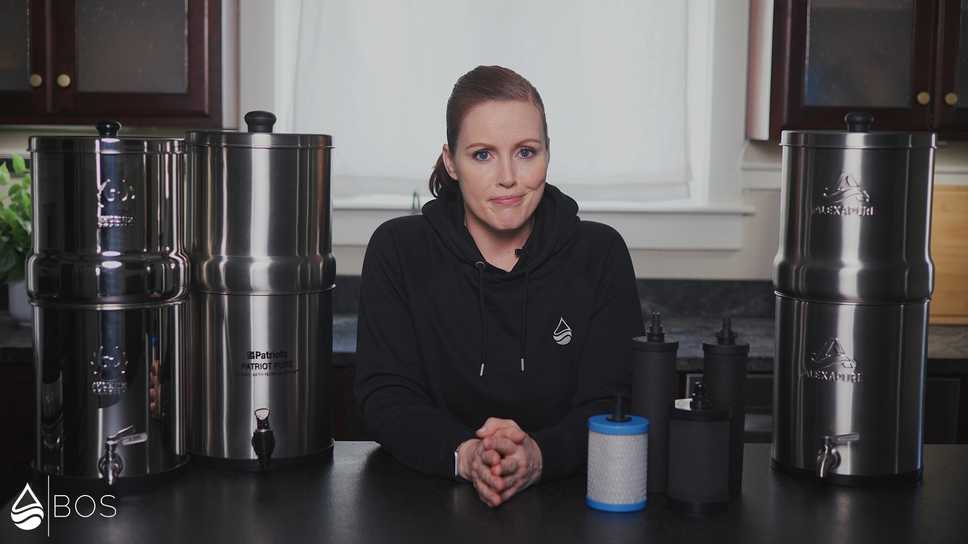 Sara in Her Kitchen With a Bunch of Gravity Water Filters in Front of Her