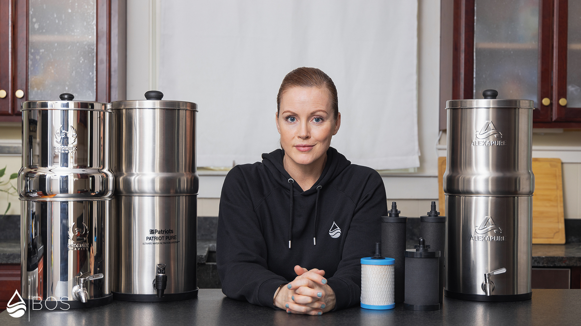 Sara in Her Kitchen With a Bunch of Gravity Water Filters in Front of Her